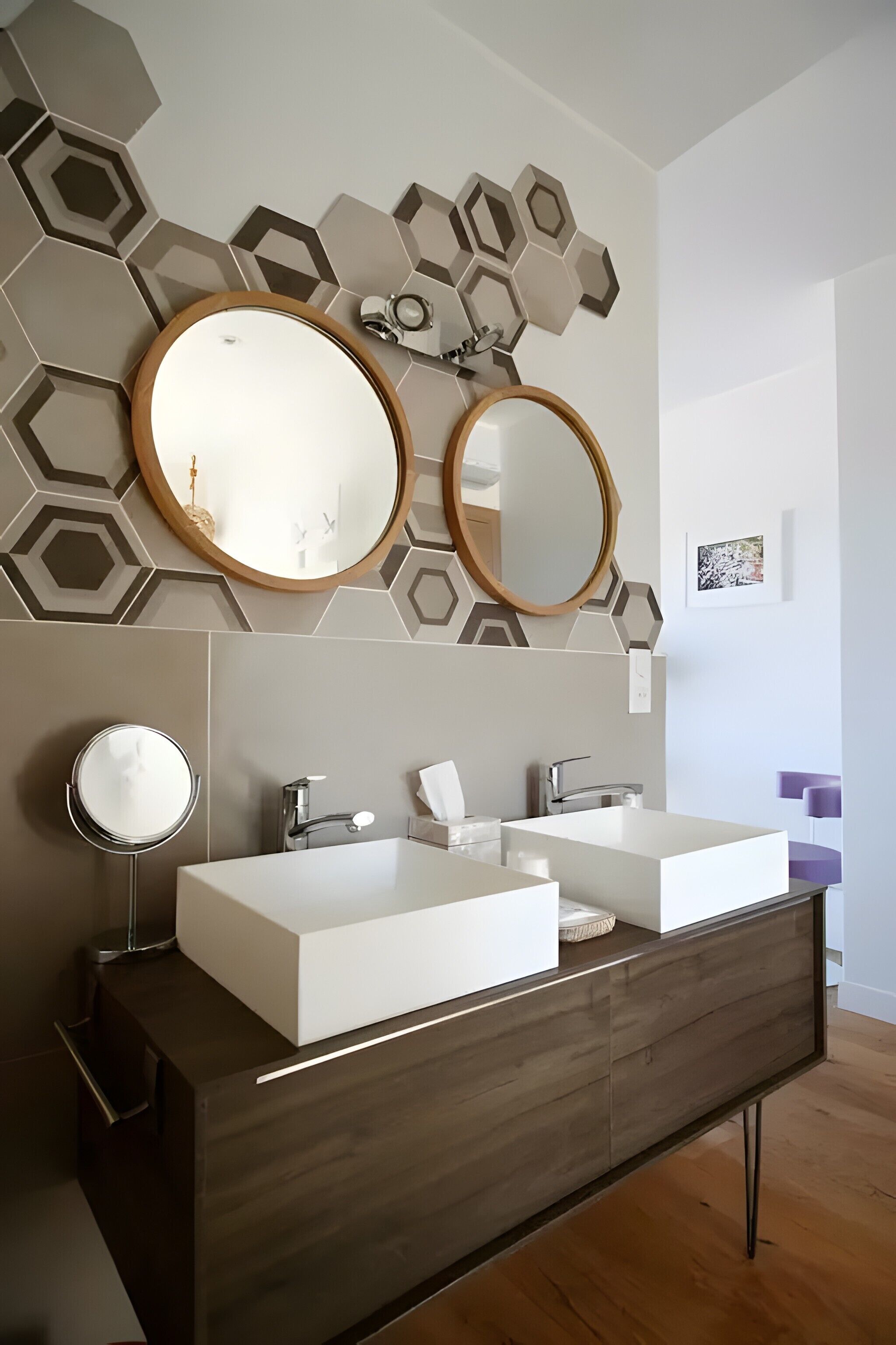 Une salle de bain moderne avec deux vasques, un meuble-lavabo et des éléments de décoration murale hexagonaux.