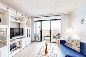 A living room with a TV, shelves, a sofa, and a balcony with outdoor furniture. - Breakwater II 202 (Ocean City)