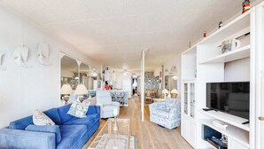Ein modernes Wohnzimmer mit einem blauen Sofa, einer weißen Unterhaltungsecke und einem Fernseher.