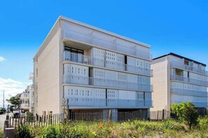 Een meerlaags woongebouw met balkons, een vlakke gevel en een houten hek op de voorgrond.