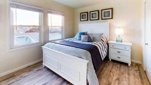 A bedroom with a bed, two bedside tables, a nightstand, and three framed pictures on the wall.