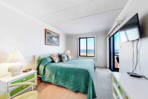 Ein Schlafzimmer mit einem Bett, einem Fernseher, einem Fenster mit Blick und einem Schreibtisch mit Schubladen.