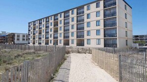 En byggnad med flera våningar, en enhetlig fasad, en central entré och ett omgivande trästaket.