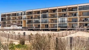 A multi-story hotel with balconies, a sandy beach in the foreground, and a clear blue sky. - Beachloft 4F (Ocean City)