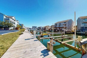 Een jachthaven met aangemeerde boten, een houten vogelzangpad en moderne gebouwen met balkons.