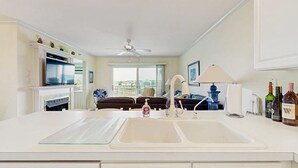 A kitchen with a double sink, a ceiling fan, a window, and a view of the outside. - Baywatch II 303D (Ocean City)