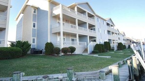 A multi-story hotel with balconies, a grassy lawn, and a dock. - Baywatch II 303D (Ocean City)