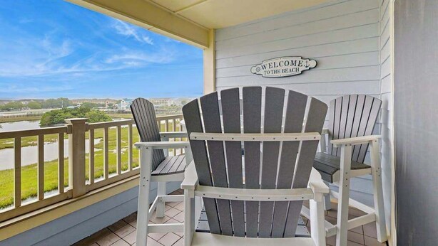 A porch with two Adirondack chairs, a ceiling fan, and a 'WELCOME TO THE BEACH' sign. - Baywatch II 303D (Ocean City)