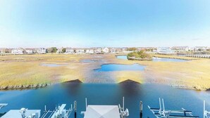 A marina with boats docked, a clear sky, and a distant view of houses and a bridge. - Baywatch II 303D (Ocean City)
