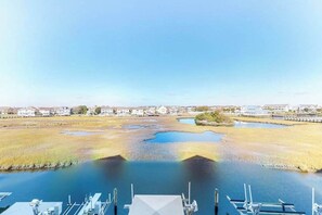 Een jachthaven met aangemeerde boten, een heldere lucht en in de verte huizen en een brug.