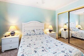A bedroom with a bed, nightstands, lamps, a mirror, and a carpeted floor. - Baywatch II 304D (Ocean City)