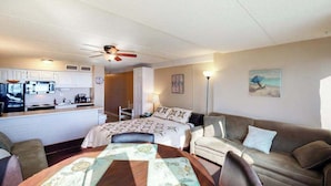 Een knus woongedeelte met een kitchenette, een eethoek, een bank en een bed.