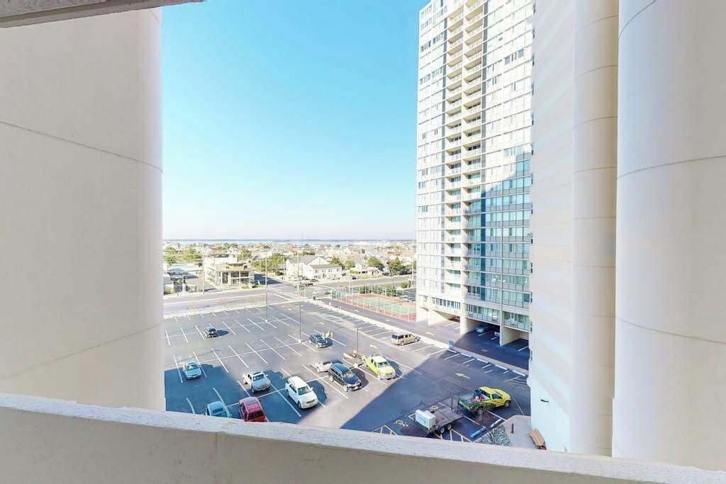 A high-rise building with a parking lot in the foreground.