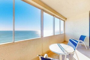 Ein Balkon mit Meerblick, einem runden Tisch und zwei Stühlen.