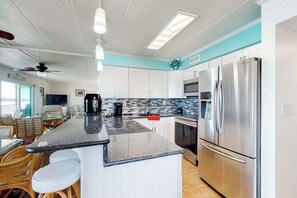 A modern kitchen with white cabinets, a stainless steel refrigerator, and a bar area with stools. - Terrific Suite in Bayfront Complex w/Shared Pool, Free WiFi, Central AC, Balcony (Ocean City)