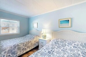 A bedroom with two beds, a nightstand with a lamp, and a framed picture on the wall. - Ann Elizabeth 204 (Ocean City)