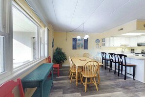 A dining area with a wooden table and chairs, a bench, a potted plant, and a kitchen in the background. - Wonderful Condo in Oceanside Building w/Free WiFi, Private Washer/Dryer (Ocean City)
