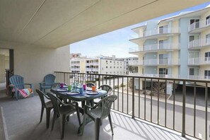 A balcony with a table set for dining, chairs, and a view of adjacent buildings. - Wonderful Condo in Oceanside Building w/Free WiFi, Private Washer/Dryer (Ocean City)
