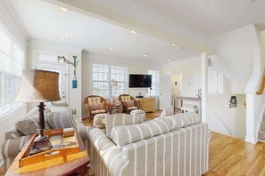 A spacious living room with a sofa set, a television, and a dining area. - 16 The Palms (Ocean City)