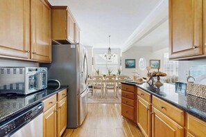A kitchen with wooden cabinets, a stainless steel refrigerator, a microwave, and a dishwasher. - 16 The Palms (Ocean City)