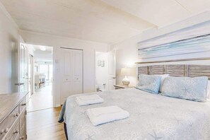 Ein Schlafzimmer mit einem Bett, zwei Nachttischen, einer Nachttischlampe und einer Tür zu einem anderen Raum.