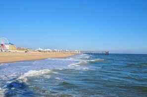 A beach with a pier extending into the water, a Ferris wheel, and buildings in the background. - Colonial Condo 202 (Ocean City)