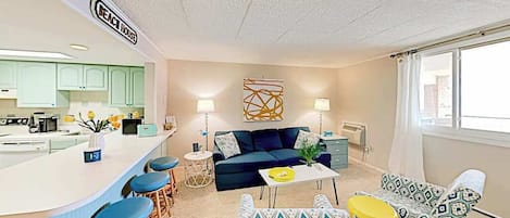 Un espacio habitable compacto con kitchenette, un sofá, una mesa de centro y una zona de comedor.