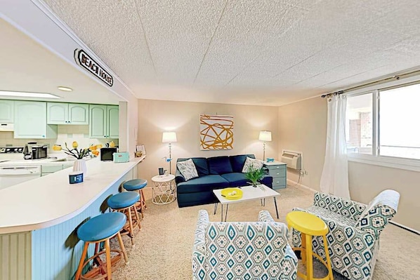 A compact living space with a kitchenette, a sofa, a coffee table, and a dining area. - Colonial Condo 202 (Ocean City)