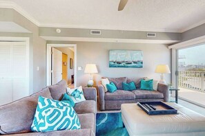 Ein Wohnzimmer mit zwei Sofas, einem Couchtisch und einem Gemälde von Segelbooten.