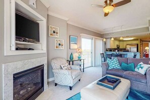 Ein Wohnzimmer mit Kamin, Fernseher, einer Couch und einem Deckenventilator.