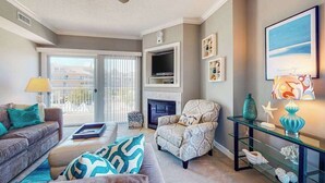 Una sala de estar con sofá, sillón, chimenea, televisión y elementos decorativos.