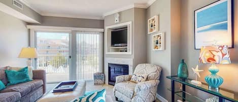 A living room with a sofa, armchair, fireplace, television, and decorative items.