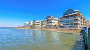 A waterfront hotel with multiple balconies, a flat roof, and a view of the water. - Sunset Island - Beachside Mews 1 & 2 (Ocean City)