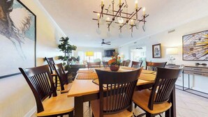 A dining area with a chandelier, wooden table, and chairs. - Bahia Vista I 403 (Ocean City)