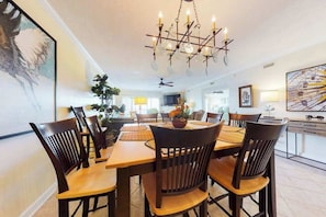 A dining area with a chandelier, wooden table, and chairs. - Bahia Vista I 403 (Ocean City)