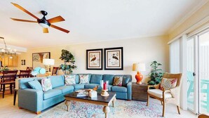 A living room with a blue sofa, a coffee table, and a ceiling fan. - Bahia Vista I 403 (Ocean City)