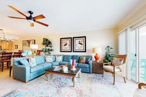 A living room with a blue sofa, a coffee table, and a ceiling fan. - Bahia Vista I 403 (Ocean City)