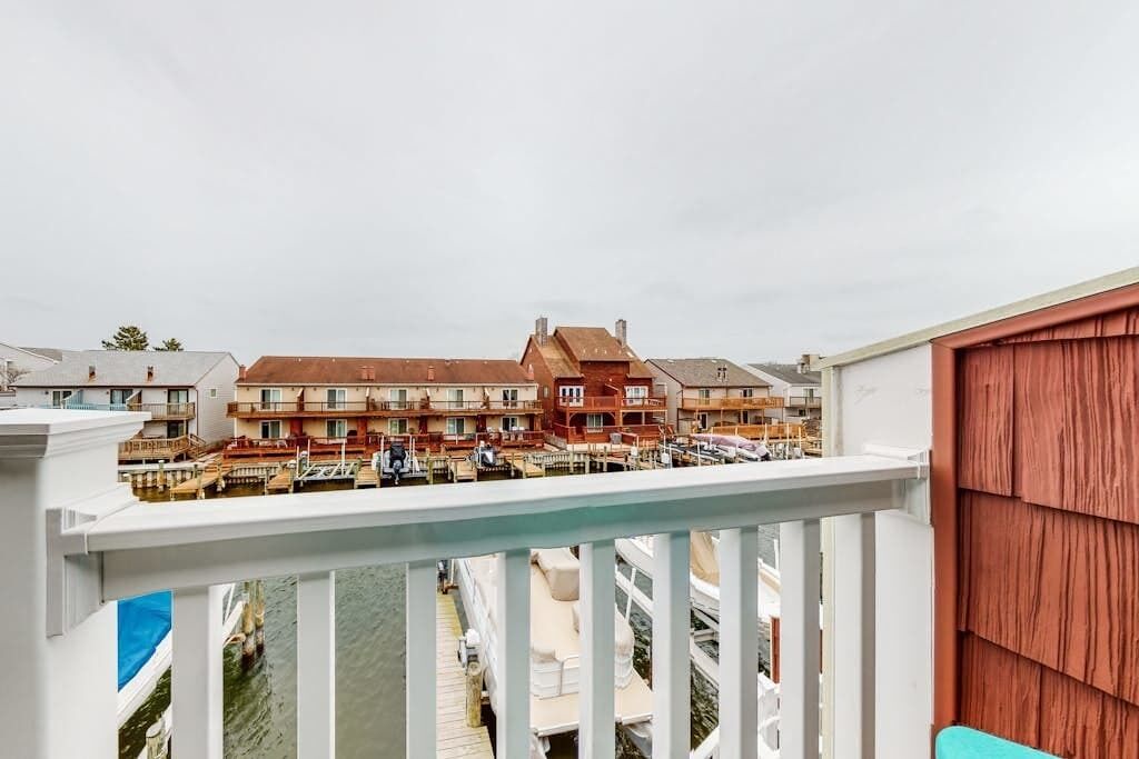 Um edifício residencial com várias varandas, uma área de cais com barcos e uma cerca de madeira.