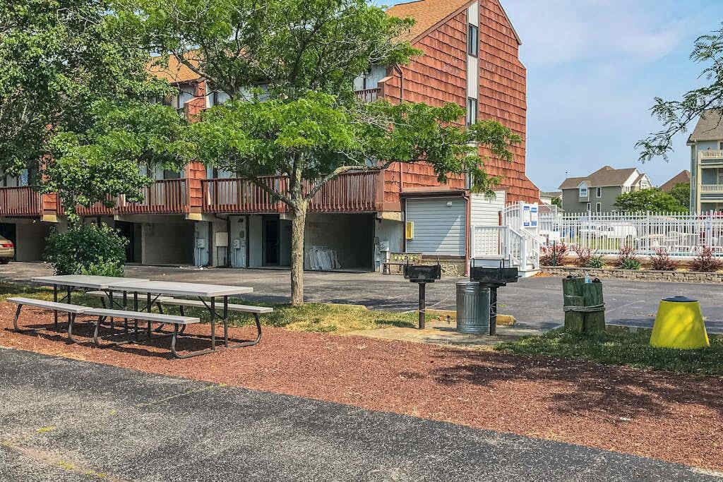 A building with a red exterior, a parking area, and a picnic table.