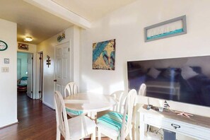 A dining area with a round table and chairs, a television, and a door leading to another room. - Condo Less than Two Miles to the Ocean with Pool, Fast WiFi, and Private W/D (Ocean City)