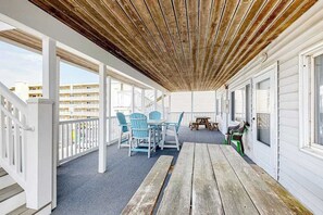 A covered outdoor area with a wooden ceiling, white railings, and a table with chairs. - The Quarterdeck Ocean Block (Ocean City)