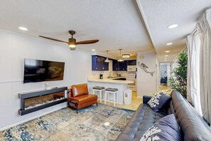 A modern living room with a flat-screen TV, leather sofa, and a fireplace. - The Quarterdeck Ocean Block (Ocean City)
