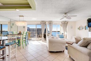 Een ruime woonkamer met balkon, een eettafel en een bank.