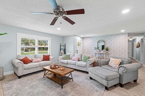 A living room with a ceiling fan, two sofas, a coffee table, and a window with blinds.