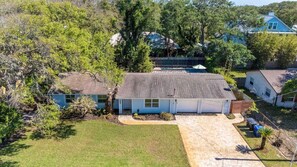 A residential property with a detached house, a covered patio, and a well-maintained lawn.