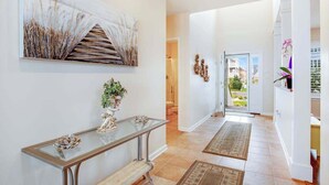 A hallway with a glass table, artwork, and a view to the outside. - A Bayfront Row Seat (Ocean City)