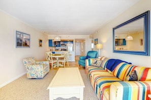 A living room with a sofa, armchair, coffee table, and a dining area with chairs and a table. - Fantastic Condo Situated in Oceanfront Complex w/Shared Pool, Free WiFi, AC (Ocean City)