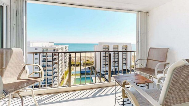 A balcony with a view of the ocean, a pool, and high-rise buildings. - Excalibur 905 (Ocean City)