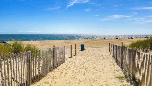A sandy beach path leading to the ocean with a clear sky. - Beachy updated condo steps from beach with fast WiFi & furnished balcony (Ocean City)