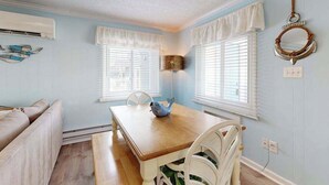 A dining area with a wooden table, white chairs, and a blue decorative bowl. - Beachy updated condo steps from beach with fast WiFi & furnished balcony (Ocean City)